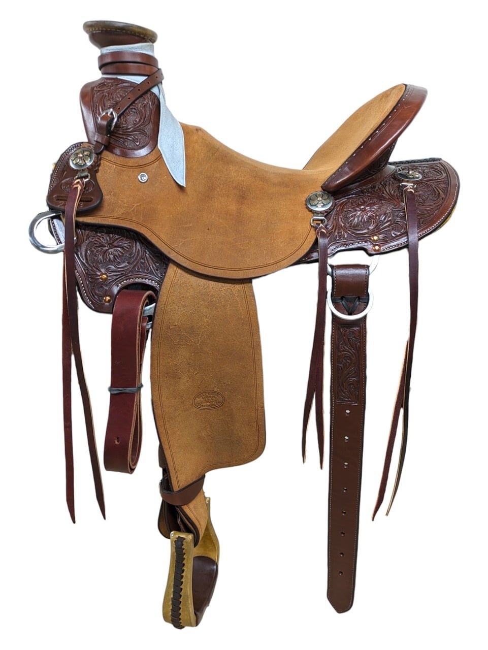 Designed for ranch and trails, this versatile all-around saddle gives you a wade front that give you more room for your thighs. It has a short rounded skirt to fit short backed horses, nice wide fit bar with flare for shoulder movement, and a roughout seat for added security and grip. The tree is reinforced with a post horn and comes with strings for all your gear and a rear flank strap. Beautiful floral tooling with border stamp is all hand-tooled by professional leather workers. Saddle Features Natural rough out seat jockey and fenders Medium oil smooth leather skirt, pommel, cantly and cheyenne roll Two line border featured on rough out Full floral tooling on smooth leather with a two line border Rounded single skirt  Easy single dropped rigging Mixed metal floral conchos with mini d-rings and tie strings Includes mule hide horn wrap and leather rope strap Includes rear cinch and rawhide covered stirrups Serial number: 102293 Saddle Specifications Cantle Height: 4.5" Horn Height: 3" Skirt Length: Approx. 24" Weight: Approx. 30 lbs Tree Size: 15.5" Seat Size: 15" Gullet: 7" mid-concho to mid-concho