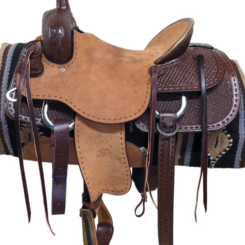 This genuine Billy Cook features a 1/2 tool of the crazy stamp tooling alongside a faux buck-stitch border. The hard rough-out seat provides a great pocket for any rider thanks to the pencil roll cantle. The dark oil stands out beautifully against the natural rough-out leather. Comes with a rear cinch and saddle strings to keep your gear close at hand. Weight: Approx. 43 lbs Gullet: 7" mid-concho to mid concho Finished Seat Size: 16" Skirt Length: 28" Tree Size: 16"