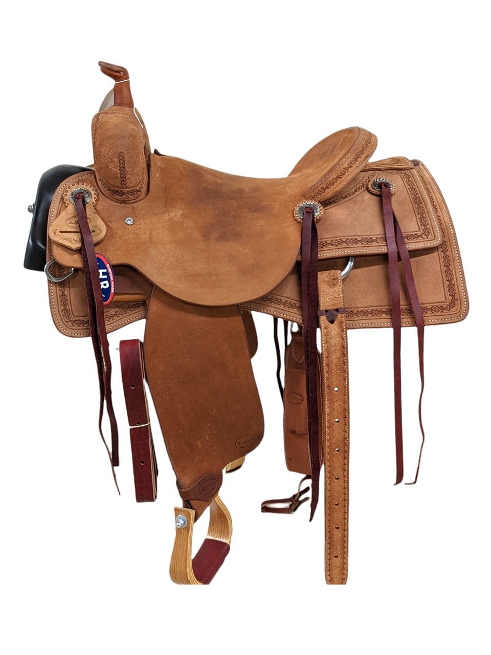 This HR Saddlery ranch cutting saddle is a stunner. This all-roughout saddle is simple which allows the diamond and barbed wire border tooling to pop! This saddle has two large, square skirts and saddle strings to keep the rider's gear close at hand. The saddle features a rough-out seat, seat jockey and fenders. This saddle's off-billet complements the saddle's light rough-out perfectly. Weight: Approx. 34 lbs Gullet: 7" mid-concho to mid concho Finished Seat Size: 15.5" Skirt Length: 27.5" Tree Size: 16"
