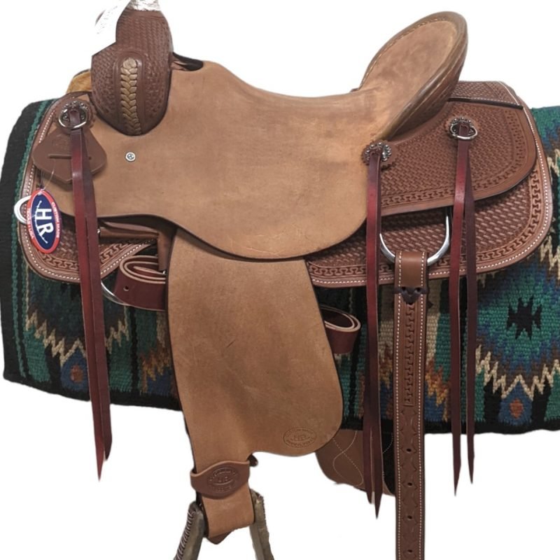 Take a look at this beautifully crafted saddle! This saddle features a rich, medium oil finish alongside a rough-out seat, seat jockey and fenders. This saddle is equipped with two skirts with rounded edges. This saddle includes silver, slotted conchos with saddle strings and silver hardware. Comes with a back-cinch. Weight: Approx. 37 lbs Gullet: 7" mid-concho to mid concho Finished Seat Size: 17" Skirt Length: 27" Tree Size: 17"
