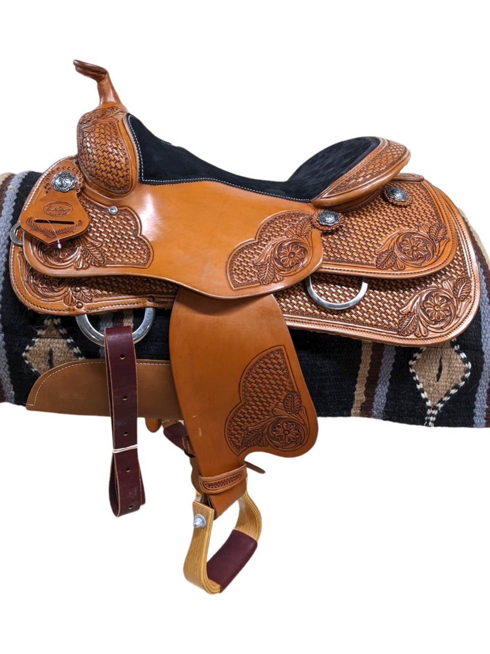 Behold this striking HR Saddlery Reiner! The light chestnut leather is embellished with a captivating blend of basket stamp and floral tooling. The black, cushioned seat ensures day-long comfort in the arena. With its enduring design, this saddle promises countless years of exceptional rides.