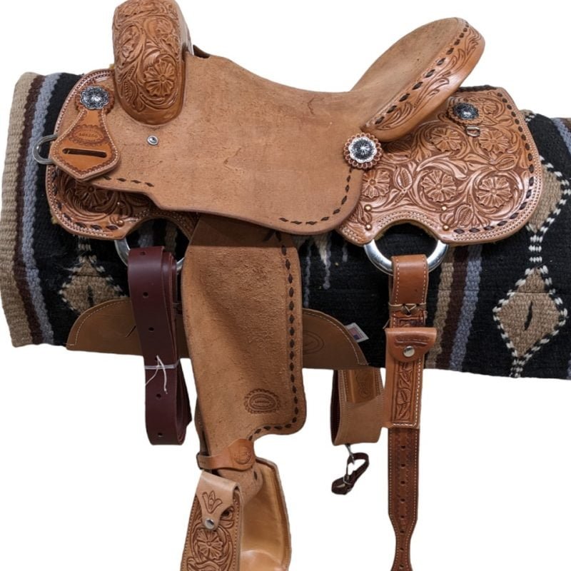 This saddle is another great hit built by Loredo! The light oil leather features a striking floral tooling and a chocolate buck-stitch. The rough-out seat, seat jockey and fenders provide the ultimate grip. Jeremiah Watt conchos accent the saddle. This all-around is the perfect saddle to compete in speed events, rope, or ride around the trails! Comes with a rear cinch and matching, tooled stirrups. Weight: Approx. 35 lbs Gullet: 7" mid-concho to mid concho Finished Seat Size: 15" Skirt Length: 25" Tree Size: 15.5"