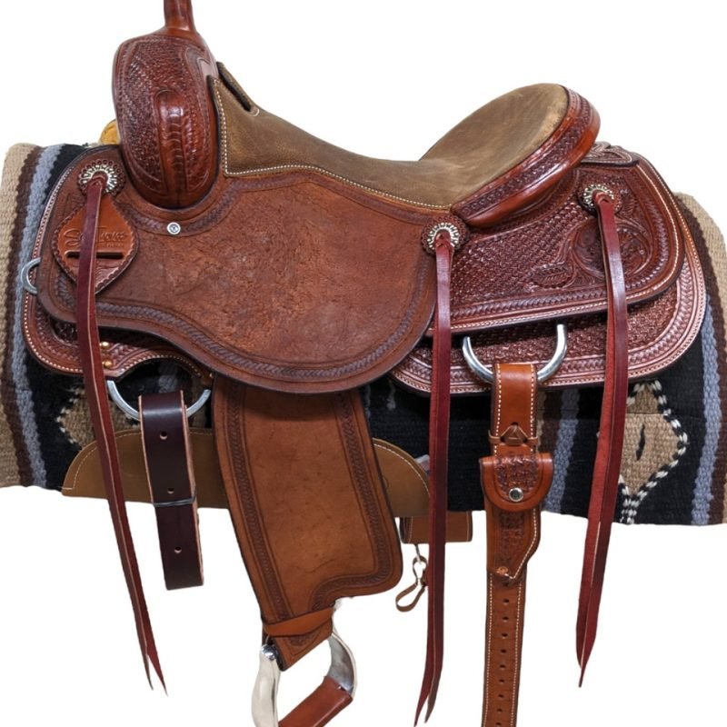 This Scott Thomas is stunning! The chestnut leather is paired alongside a rustic, tan padded seat. The rough-out seat jockey and fenders provides the perfect grip. The combination crazy leg and floral tooling makes this functional saddle also beautiful. Comes with a rear cinch and saddle strings. Weight: Approx. 37 lbs Gullet: 7" mid-concho to mid concho Finished Seat Size: 16" Skirt Length: 29" Tree Size: 16.5"