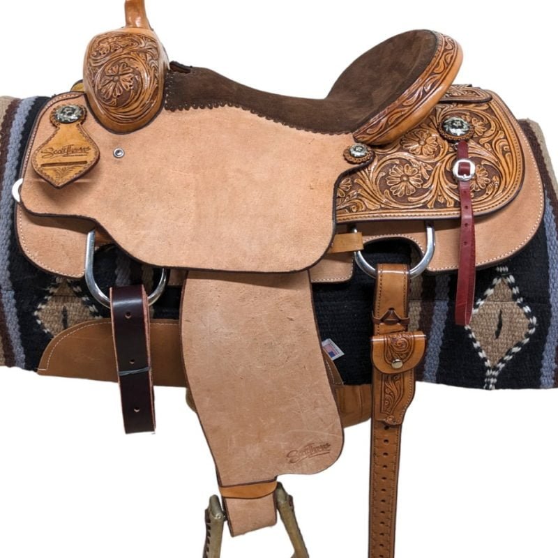 This exquisite Scott Thomas Western Roper is crafted with natural leather, featuring intricate floral tooling and a light antique finish. The chocolate padded seat, adorned with pop-stitching, ensures a comfortable ride for extended periods. Complete with a rear cinch, this saddle combines style and comfort for all-day riding enjoyment.